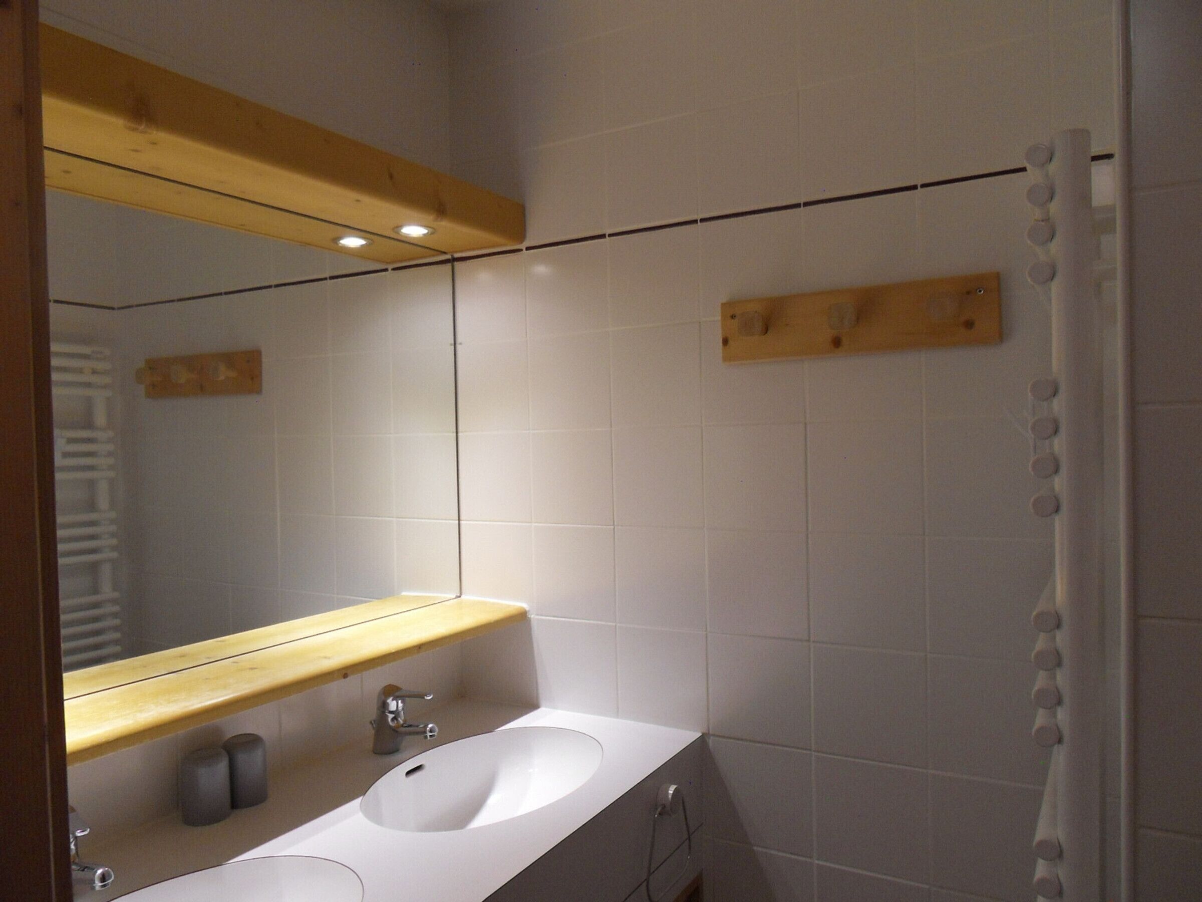 A bathroom with a white sink, wooden shelf, and a shower curtain.