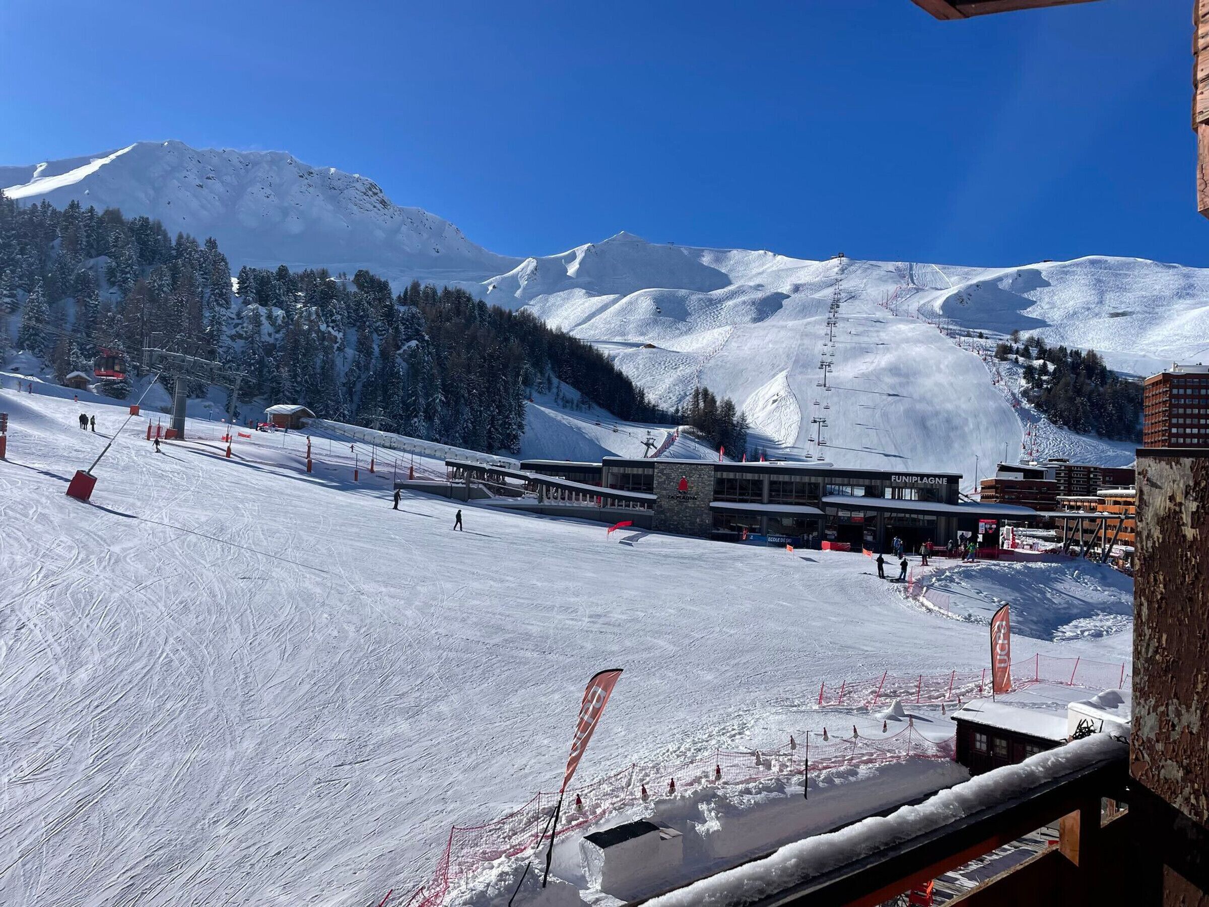 A ski resort with a ski lift, buildings, and snow-covered mountains.