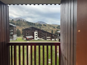 A wooden balcony with a view of a mountain lodge with multiple floors and balconies.