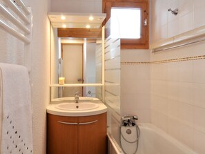 Een badkamer met een wastafel, spiegel en douche.