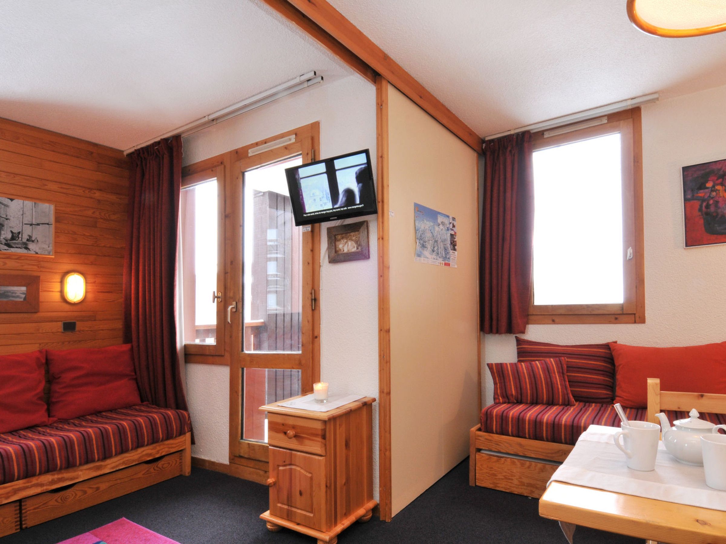 Ein gemütliches Zimmer mit zwei Holzbetten, einem kleinen Nachttisch, einem Fernseher und einem Tisch mit Teekanne und Tassen.