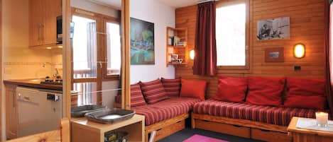 Interior acogedor de una cabaña con kitchenette, sofá cama y comedor.