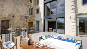 Une terrasse extérieure avec une table à manger dressée pour un repas, entourée de chaises à rayures.