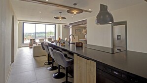 Une cuisine moderne dotée d’un îlot central, de tabourets de bar et d’une grande fenêtre donnant sur la campagne.