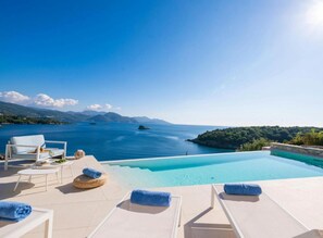 Un espace aménagé au bord de la piscine, avec des chaises longues et une vue sur la mer.