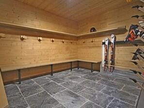 A ski lodge with benches, a stone floor, and ski racks.