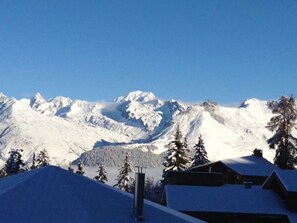 A snow-covered mountain range with a cabin in the foreground.