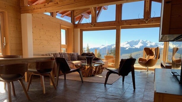 A spacious room with a wooden interior, a stone floor, and large windows offering a mountain view. - Spacious Renovated Chalet · Terrace · Sleeps 10 · Free Wifi (Les Arcs 1800)