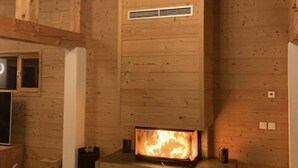 A wooden cabin interior with a fireplace, wooden walls, and a window. - Spacious Renovated Chalet · Terrace · Sleeps 10 · Free Wifi (Les Arcs 1800)