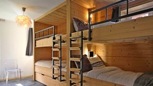 Une chambre avec un lit superposé, une échelle, une chaise et un tapis moelleux.