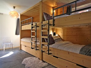 Een slaapkamer met een stapelbed, een ladder, een stoel en een zacht vloerkleed.