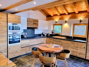 A modern kitchen with wooden cabinetry, a round dining table, and built-in appliances.