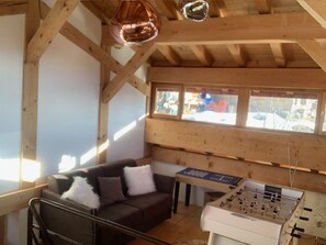 Una habitación acogedora con un sofá, una mesa de fútbol de mesa y una ventana que ofrece vistas al exterior.