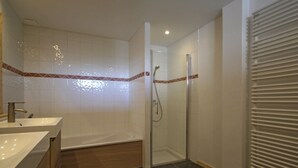 A modern bathroom with two sinks, a bathtub, and a glass-enclosed shower. - Spacious Renovated Chalet · Terrace · Sleeps 10 · Free Wifi (Les Arcs 1800)