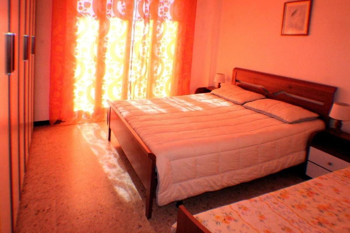 Un dormitorio con una cama, una mesita de noche y una ventana con cortinas.