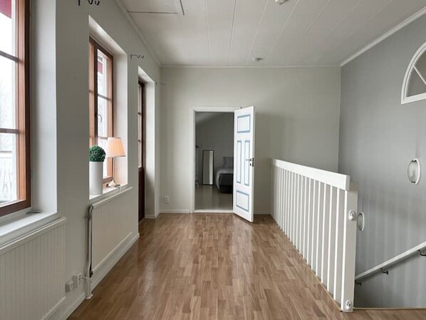 A hallway with wooden flooring, white walls, and a white radiator. - Timrå Farmhouse, large villa 222sqm in central Timrå yet on a private location. (Timrå, Västernorrlands län)