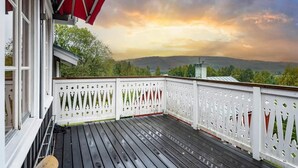 A wooden deck with a white picket fence, overlooking a hilly landscape during sunset. - Timrå Farmhouse, large villa 222sqm in central Timrå yet on a private location. (Timrå, Västernorrlands län)