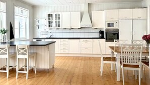 A spacious kitchen with white cabinetry, a central island, and wooden flooring. - Timrå Farmhouse, large villa 222sqm in central Timrå yet on a private location. (Timrå, Västernorrlands län)