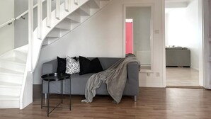 A modern interior with a staircase, a grey sofa, a small round table, and a door leading to another room. - Timrå Farmhouse, large villa 222sqm in central Timrå yet on a private location. (Timrå, Västernorrlands län)