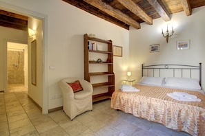 Un dormitorio con cama, una silla, una estantería y baño.