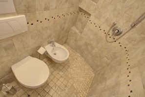 Un baño con inodoro, bidé y ducha.