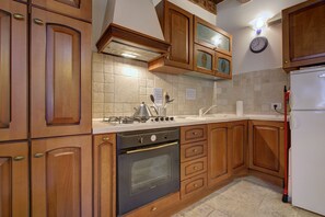 Una cocina con armarios de madera, estufa, horno y refrigerador.