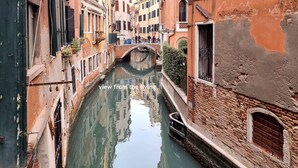 Un canal estrecho flanqueado por edificios, un puente y vistas desde la sala.