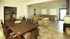 A spacious living area with a wooden dining table, a sectional sofa, and wicker furniture. - Sandy Feet Langebaan 8-sleeper (Langebaan)