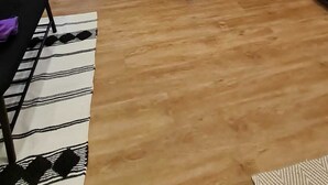 Un saló modern amb una taula de dinar de fusta, cadires negres, un sofà i una catifa petita.