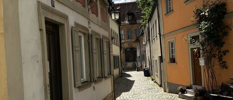 A cobblestone street lined with historic buildings, narrow passageway, and a clear sky.