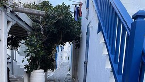 A narrow stone-paved alleyway flanked by white buildings with blue railings. - Mykonos Chora 2 Bd House Cycladic Escape (Mykonos)