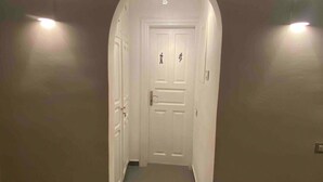 A hallway with a white door at the end, flanked by two wall-mounted lights. - Mykonos Chora 2 Bd House Cycladic Escape (Mykonos)