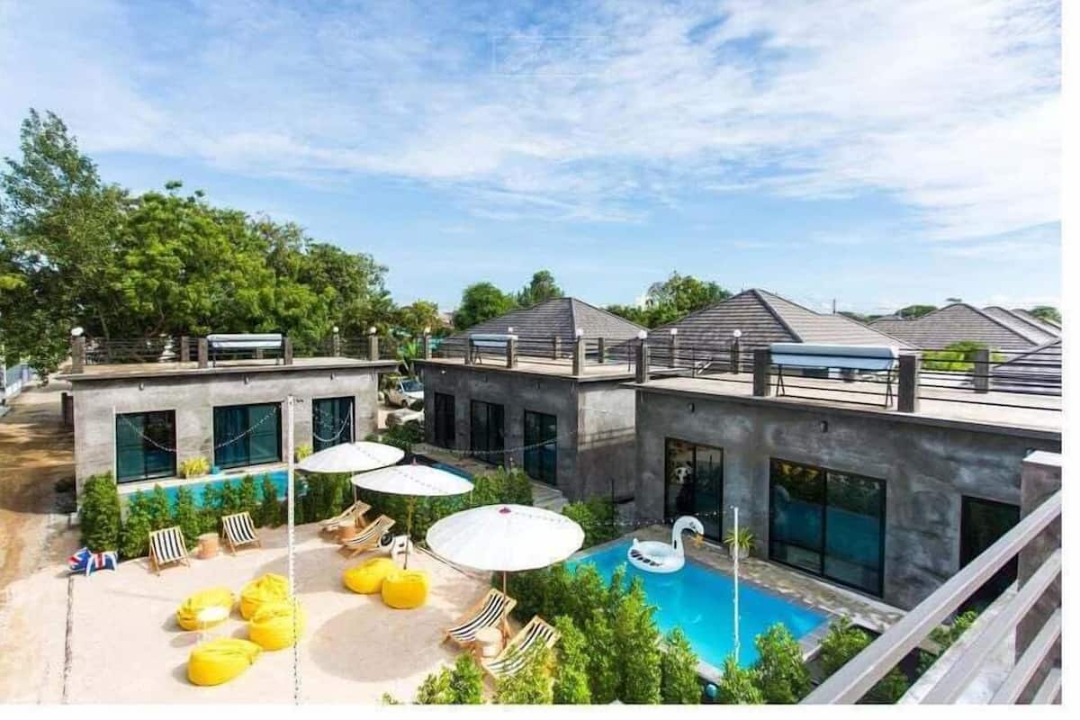 A modern building with a rooftop pool area, including lounge chairs and umbrellas.