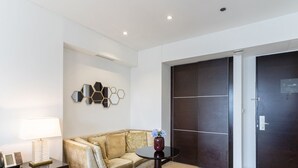 A modern room with a sofa, a round table, a vase with flowers, and a wall-mounted mirror arrangement. - Elegant Studio Address Marina (Dubai)