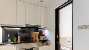A modern kitchen with stainless steel appliances, a black countertop, and a wooden cutting board. - Elegant Studio Address Marina (Dubai)