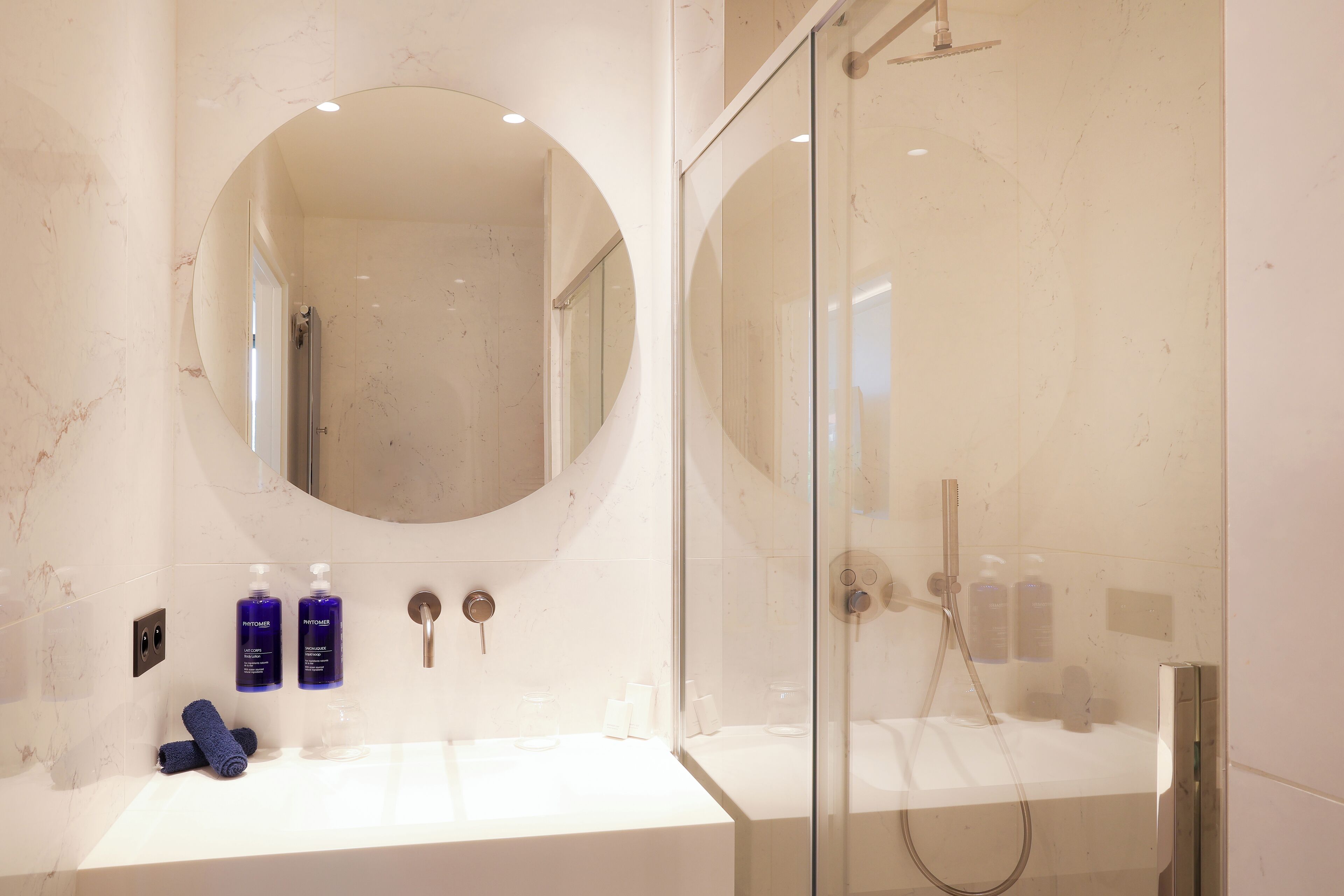 Une salle de bain moderne avec un grand miroir, deux lavabos et une douche à parois de verre.