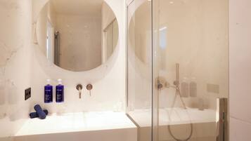 Une salle de bain moderne avec un grand miroir, deux lavabos et une douche à parois de verre.
