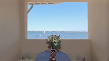 Une pièce avec vue sur la mer, une table ornée d’un vase de fleurs et une chaise.