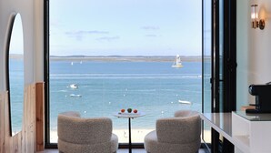 A modern room with a large window overlooking the sea, featuring two chairs and a small table. - Les Vagues Hôtel & Spa (Arcachon)