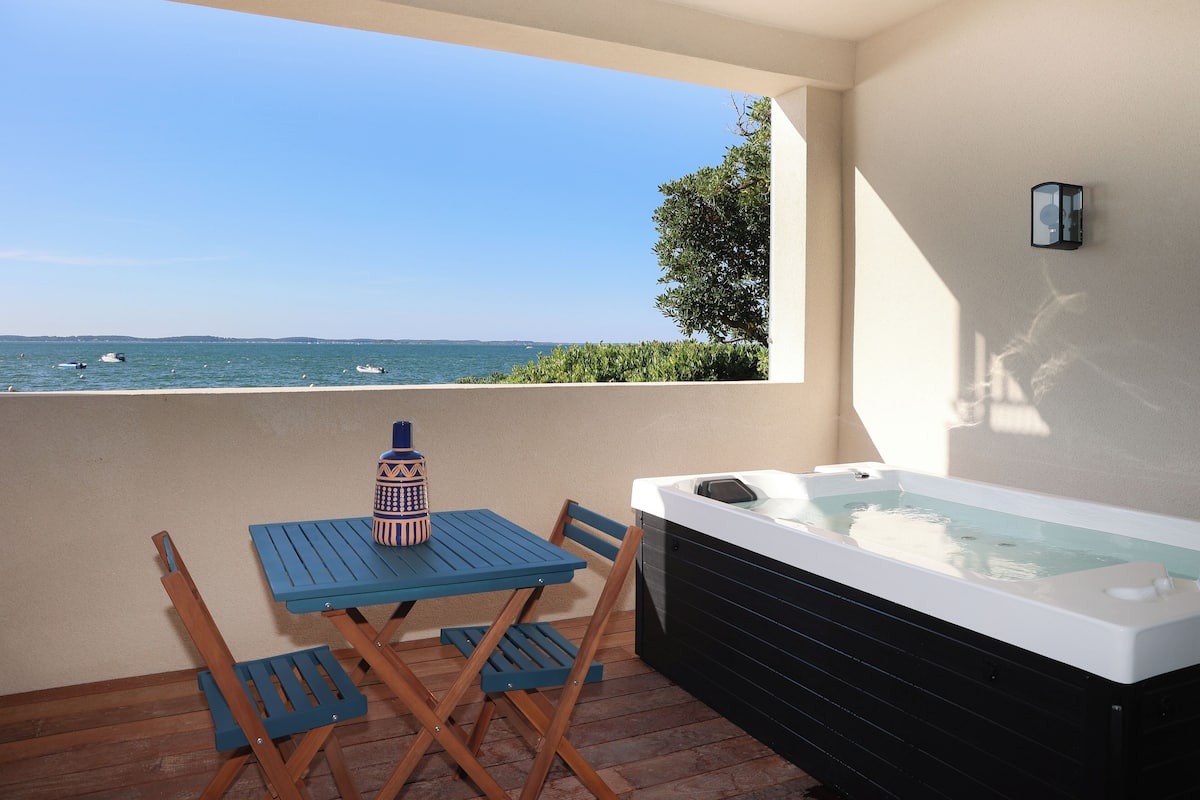 A balcony with a table, chairs, and a hot tub.