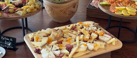 A buffet with various food items including fruits, cheeses, and meats.