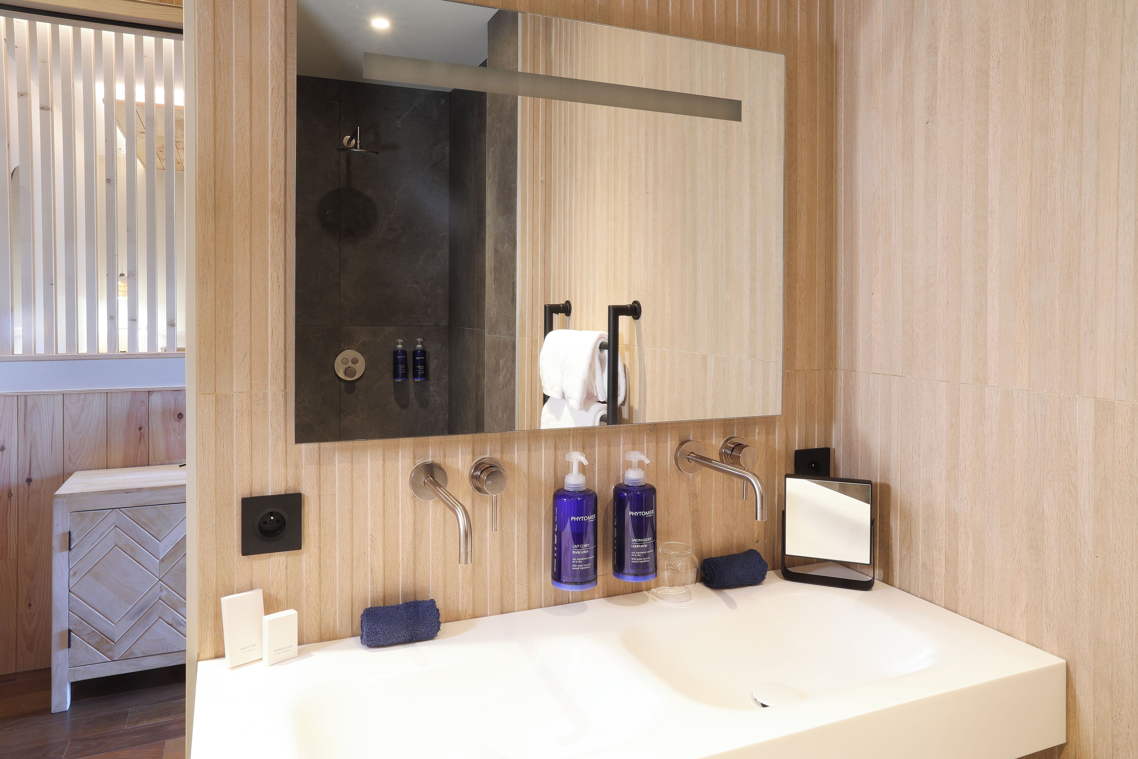 A modern bathroom with a large sink, a mirror, and a shower.