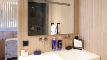 A modern bathroom with a large sink, a mirror, and a shower.