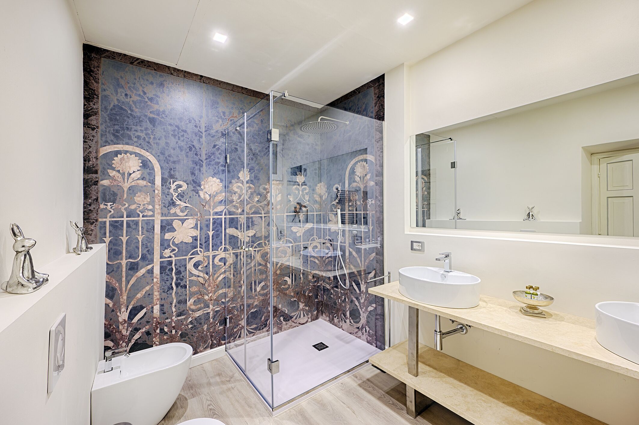 Un baño moderno con ducha acristalada, un espejo grande y dos lavamanos.