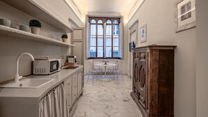 Una cocina estrecha con un lavamanos blanco, un microondas y un armario de madera.