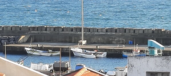 A marina with several boats docked, a concrete breakwater, and a small building with a blue roof. - Sunrise House - 4 Quartos com um Nascer do sol Incrível (Vila Franca Do Campo)