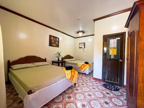 Une chambre d’hôtel avec deux lits, une petite table, une plante en pot et une porte sur laquelle est affiché un avis.