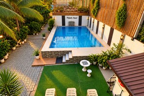 A swimming pool with a wooden deck and a small garden area with a chess table. - Delgados Resort Puerto Galera powered by Cocotel (Puerto Galera)