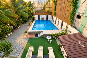 A rooftop swimming pool with a view of the city, surrounded by greenery and potted plants. - Delgados Resort Puerto Galera powered by Cocotel (Puerto Galera)
