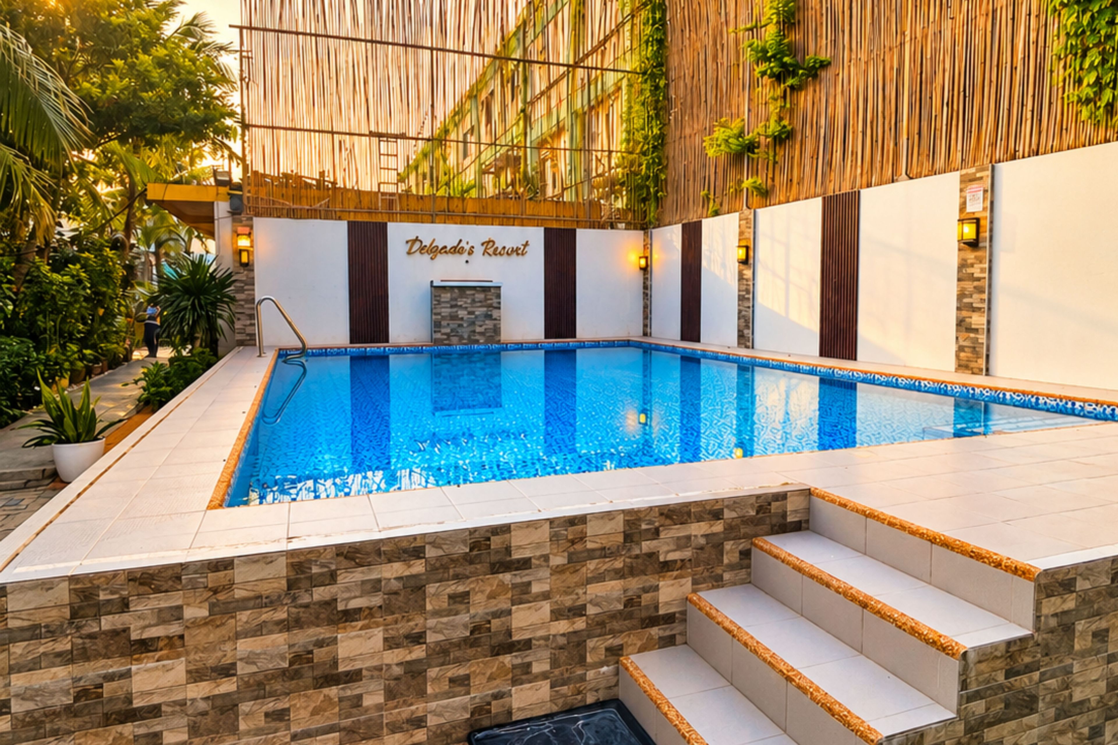 Una piscina con borde de baldosas de piedra, terraza de madera y un cartel que dice 'Delgado's Resort'.